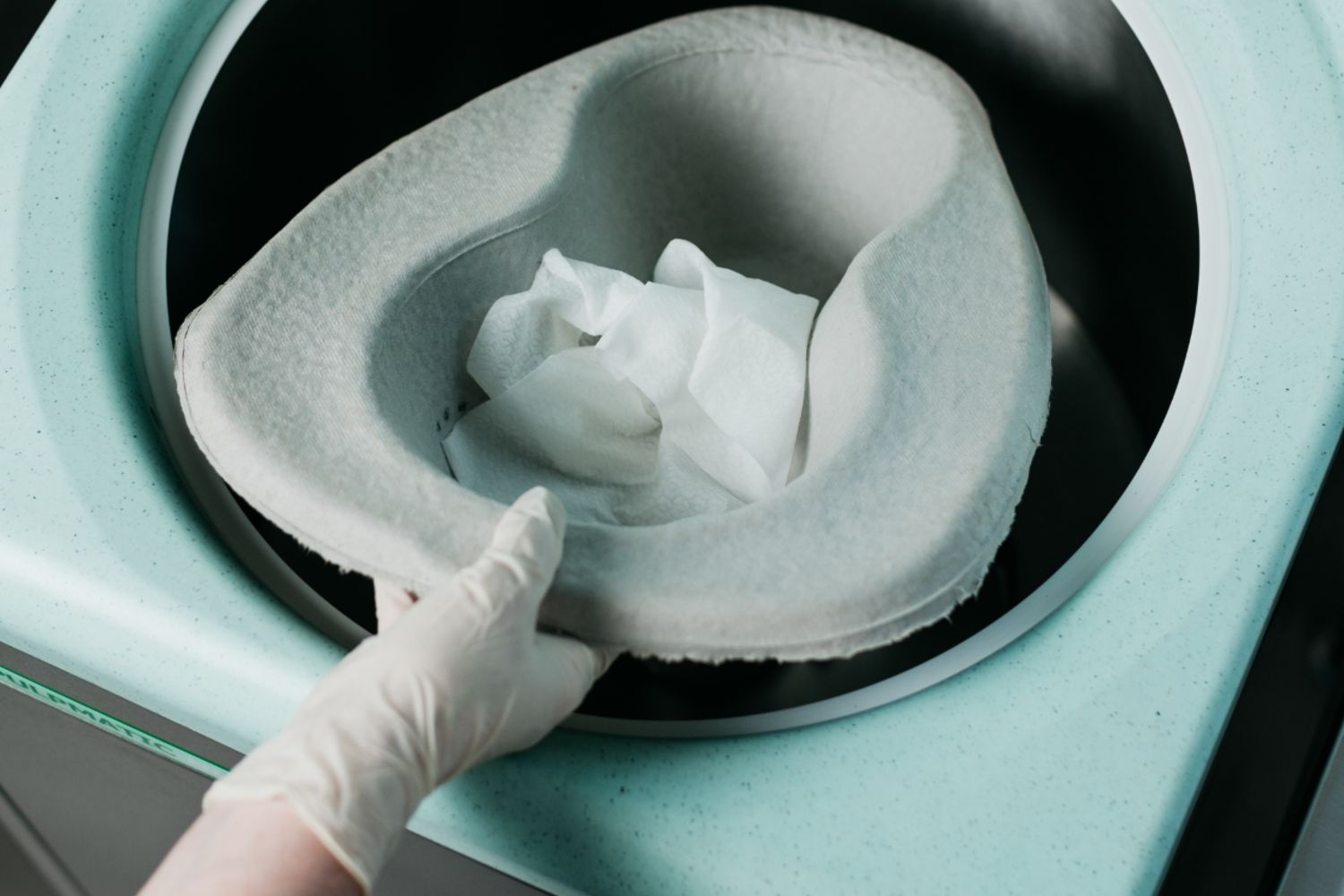 Hand Placing Pulp Bedpan and Wipes in Macerator